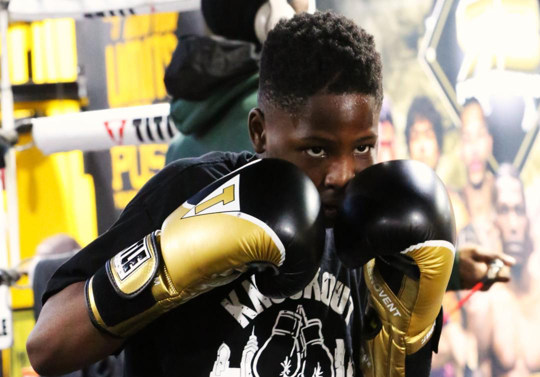 Young boxer in fighting stance with gold and black boxing gloves